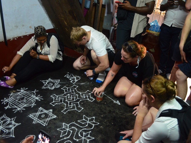 Guests Trying Floral patterns or Kolam in Kochi Sightseeing Tour